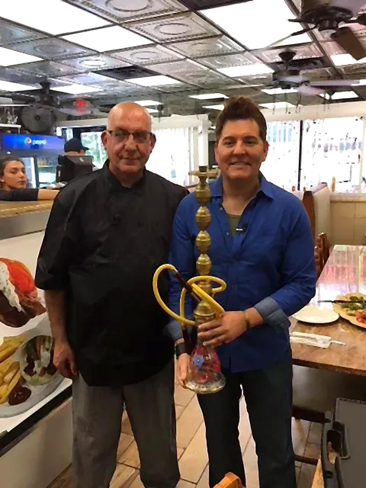 Two guests holding a hookah inside the restaurant