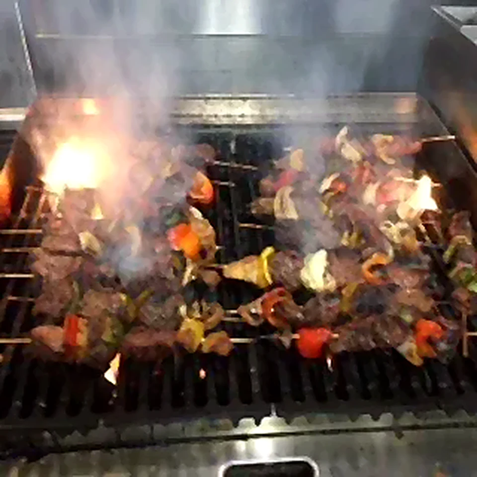 Skewers cooking over a flaming grill